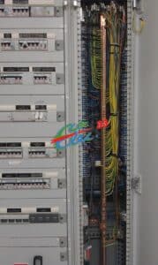 Armoire électrique ouverte montrant rangées de disjoncteurs et câblage interne ordonné avec barre de terre en cuivre et borniers. Textes: 'GENERAL BAR 1', 'PROTECTION PARTICULIÈRE'.
